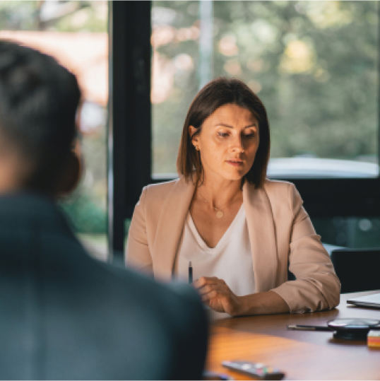 An image of a woman sitting at a desk and looking at her phone.